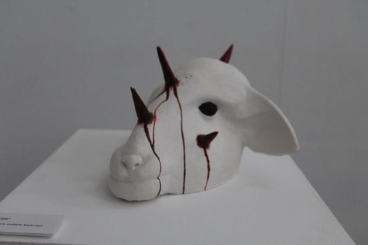 White 'Sacrificial Lamb' sculpture with spikes and red markings on display.